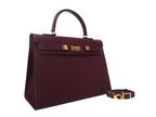 A large taupe colored Italian calf leather handbag with pebble print texture, gold plated hardware, and a top handle with a detachable strap.
