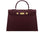 A large wine colored Italian calf leather handbag with pebble print texture, gold plated hardware, and a top handle with a detachable strap.