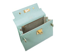 Inside view of a medium-sized luxury Italian leather handbag in a soft aqua pale turquoise color with a grainy texture, featuring a top handle, a detachable shoulder strap and gold-plated hardware