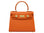 An orange luxury handbag with a top handle and gold-plated hardware, made of Italian calf leather.